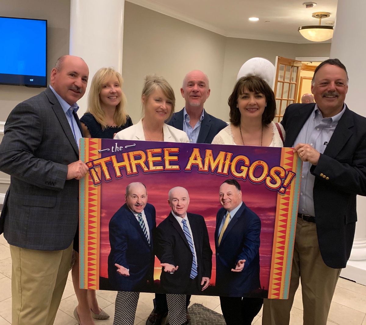 group of people holding three amigos sign